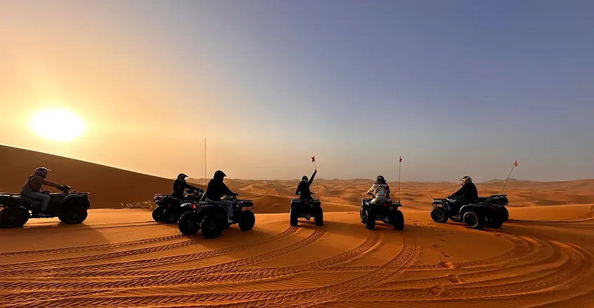 foto de clientes de 1001 Tours Morocco con quads al atardecer entre las dunas